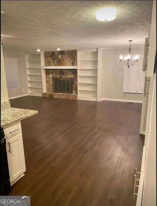 2058 Pair Rd SW, Marietta, GA 30008 - unfurnished living room with baseboards, built in features, dark wood finished floors, a chandelier, and a textured ceiling