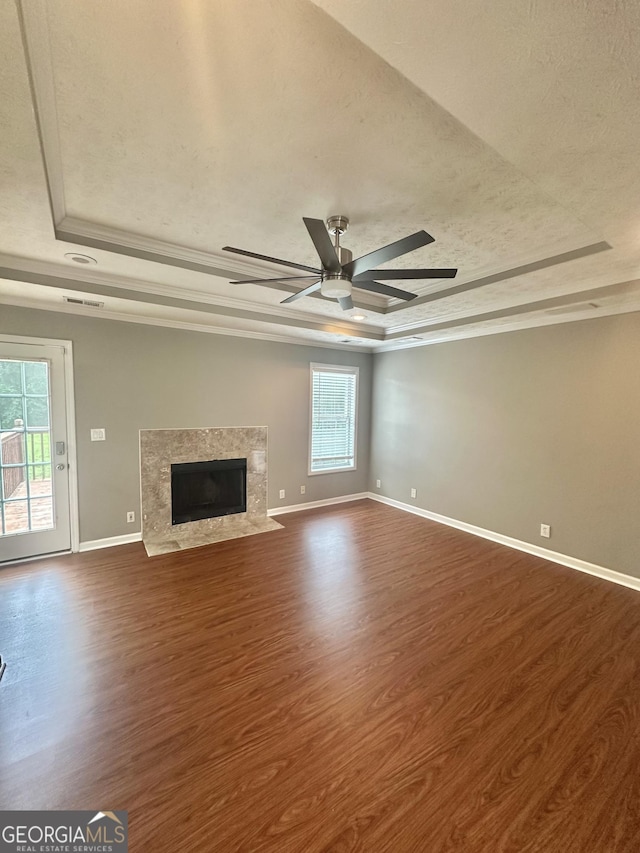 80 Fields Creek Way, Covington, GA 30016 - unfurnished living room featuring a tray ceiling, dark wood-type flooring, a premium fireplace, ornamental molding, and a ceiling fan