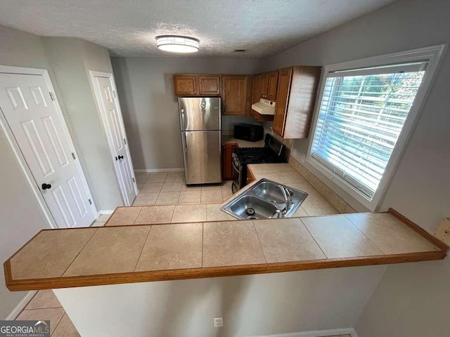 3251 Avensong Village Cir, Milton, GA 30004 - kitchen with freestanding refrigerator, gas stove, a sink, brown cabinets, and tile counters