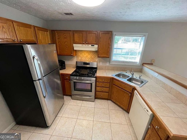 3251 Avensong Village Cir, Milton, GA 30004 - kitchen with stainless steel appliances, under cabinet range hood, a sink, tile countertops, and brown cabinetry