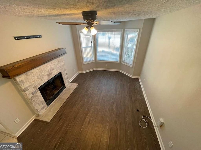 3251 Avensong Village Cir, Milton, GA 30004 - unfurnished living room with dark wood-type flooring, ceiling fan, a textured ceiling, and a tiled fireplace