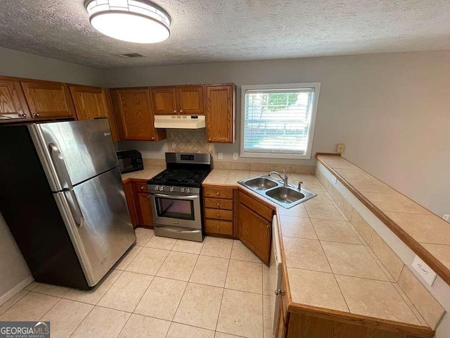 3251 Avensong Village Cir, Milton, GA 30004 - kitchen with appliances with stainless steel finishes, under cabinet range hood, tile counters, brown cabinets, and light tile patterned floors