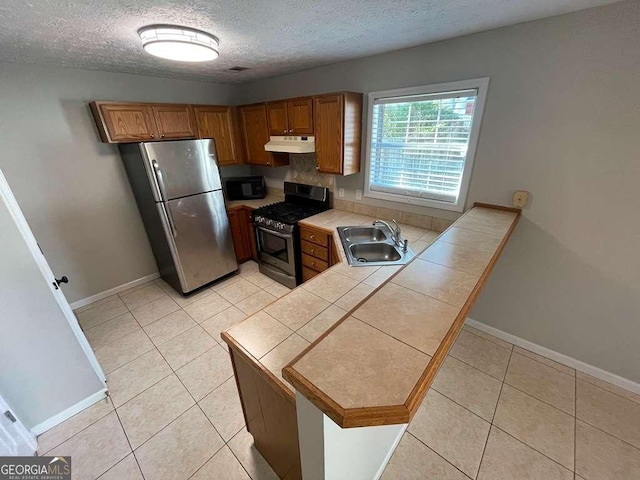 3251 Avensong Village Cir, Milton, GA 30004 - kitchen with stainless steel appliances, under cabinet range hood, tile countertops, a textured ceiling, and brown cabinets