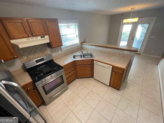 3251 Avensong Village Cir, Milton, GA 30004 - kitchen with stainless steel range with gas stovetop, under cabinet range hood, dishwasher, tile countertops, and a peninsula