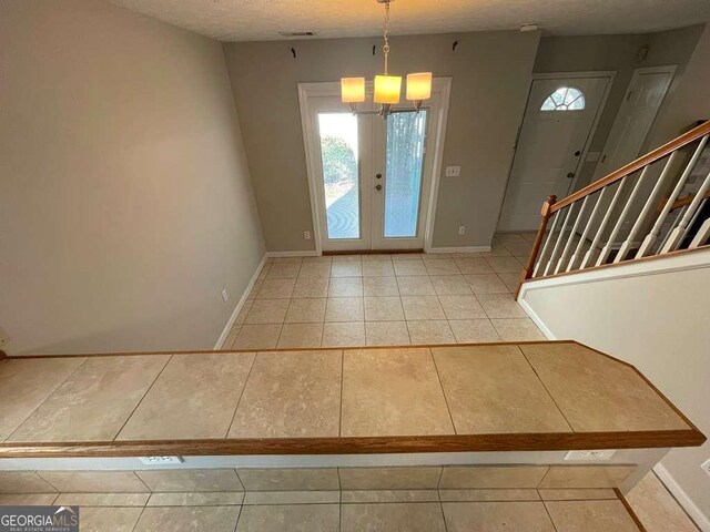 3251 Avensong Village Cir, Milton, GA 30004 - foyer entrance featuring light tile patterned floors, a chandelier, healthy amount of natural light, and a textured ceiling