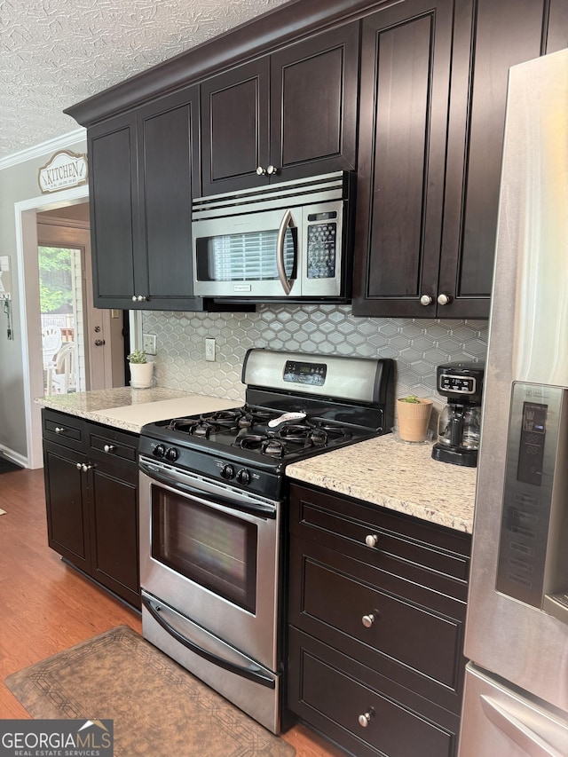 60 Buck Trl, Newnan, GA 30265 - kitchen featuring appliances with stainless steel finishes, backsplash, ornamental molding, light wood-type flooring, and a textured ceiling