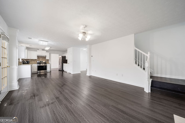 773 Minor Oaks Run NW, Lilburn, GA 30047 - unfurnished living room with a textured ceiling, dark wood-style flooring, ceiling fan, and stairs