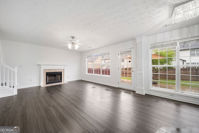 773 Minor Oaks Run NW, Lilburn, GA 30047 - unfurnished living room featuring a ceiling fan, dark wood-type flooring, a textured ceiling, a fireplace with flush hearth, and stairs