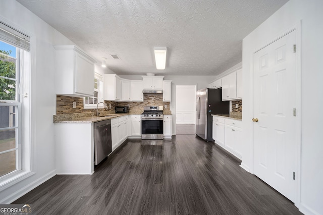 773 Minor Oaks Run NW, Lilburn, GA 30047 - kitchen with appliances with stainless steel finishes, dark wood finished floors, backsplash, white cabinetry, and a textured ceiling
