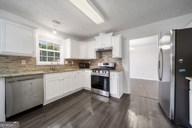 773 Minor Oaks Run NW, Lilburn, GA 30047 - kitchen featuring stainless steel appliances, under cabinet range hood, dark wood-type flooring, white cabinets, and a textured ceiling