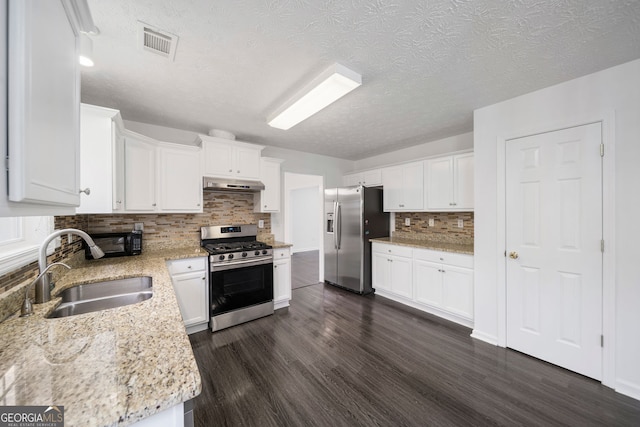 773 Minor Oaks Run NW, Lilburn, GA 30047 - kitchen featuring stainless steel appliances, under cabinet range hood, dark wood-style flooring, decorative backsplash, and a textured ceiling