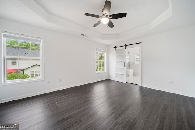 773 Minor Oaks Run NW, Lilburn, GA 30047 - empty room featuring a tray ceiling, a barn door, ornamental molding, dark wood-type flooring, and plenty of natural light