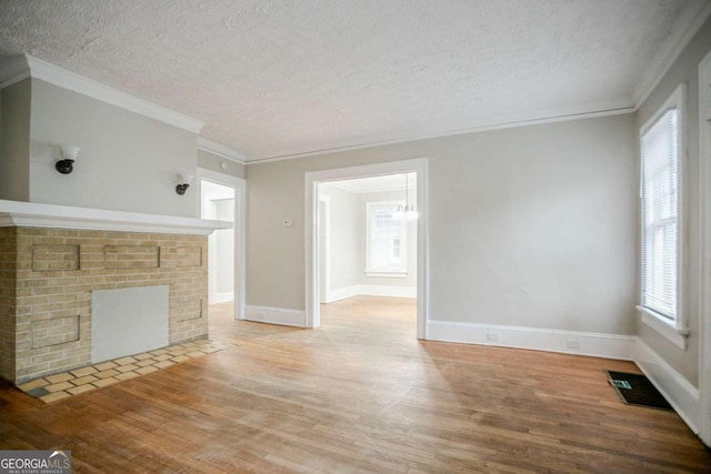 1615 Stokes Ave SW, Atlanta, GA 30310 - unfurnished living room with wood finished floors, a textured ceiling, crown molding, a brick fireplace, and a chandelier