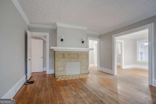 1615 Stokes Ave SW, Atlanta, GA 30310 - unfurnished living room featuring hardwood / wood-style floors, a textured ceiling, ornamental molding, and a brick fireplace