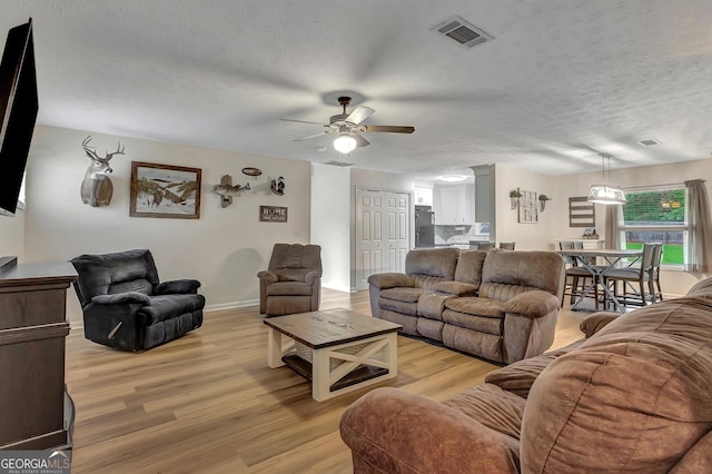 10 1st Ave E, Newnan, GA 30265 - living room featuring light wood-style flooring, a ceiling fan, a textured ceiling, and baseboards