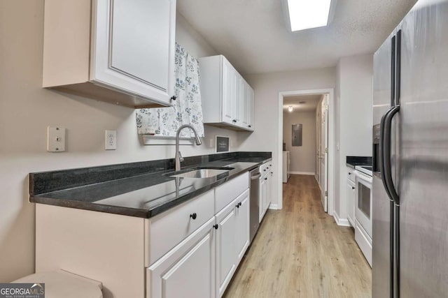 40 Moore Rd, Newnan, GA 30263 - kitchen with stainless steel appliances, a sink, white cabinetry, light wood finished floors, and dark countertops