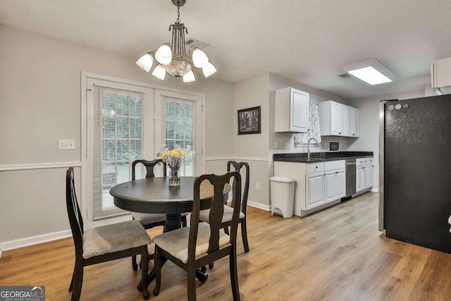 40 Moore Rd, Newnan, GA 30263 - dining area with a chandelier, light wood-type flooring, a textured ceiling, and baseboards