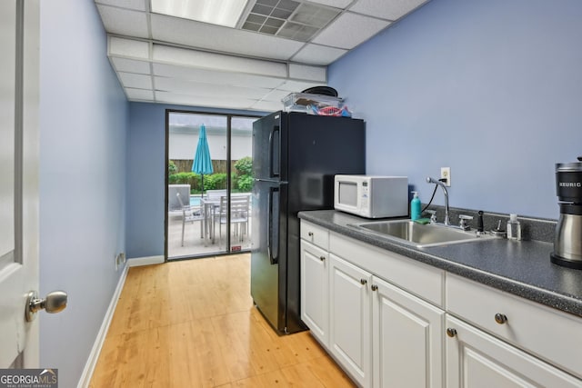 209 14th St NE Unit 109, Atlanta, GA 30309 - kitchen featuring white microwave, white cabinetry, light wood finished floors, dark countertops, and freestanding refrigerator