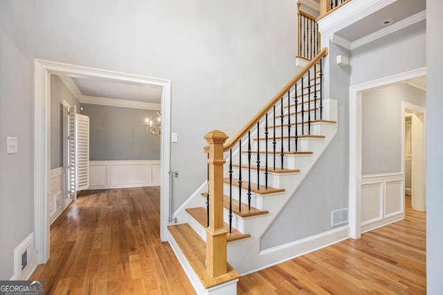 386 Link Rd, Alpharetta, GA 30022 - staircase with a decorative wall, wood finished floors, ornamental molding, a wainscoted wall, and a chandelier
