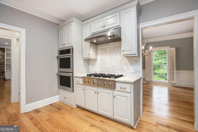 386 Link Rd, Alpharetta, GA 30022 - kitchen with appliances with stainless steel finishes, under cabinet range hood, crown molding, decorative backsplash, and light wood-style floors