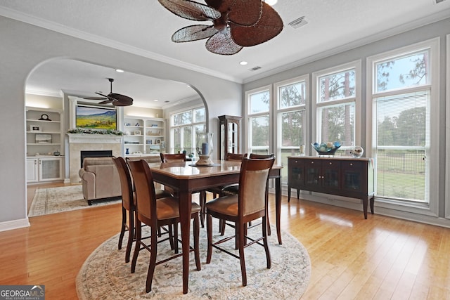 12 Par Dr, Jesup, GA 31546 - dining room featuring ceiling fan, ornamental molding, a tiled fireplace, arched walkways, and light wood-style floors
