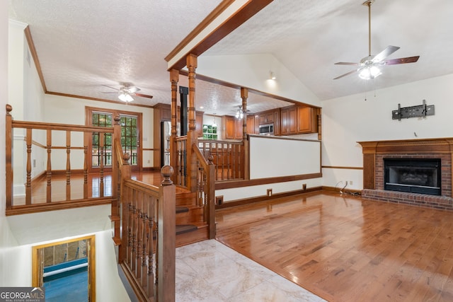 48 Saddle Field Cir, Cartersville, GA 30121 - living room featuring a ceiling fan, a fireplace, a textured ceiling, lofted ceiling, and light wood-style floors