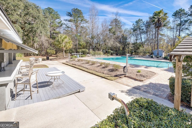 79 Churchill Ct, Richmond Hill, GA 31324 - community pool with a patio, a storage unit, and view of wooded area