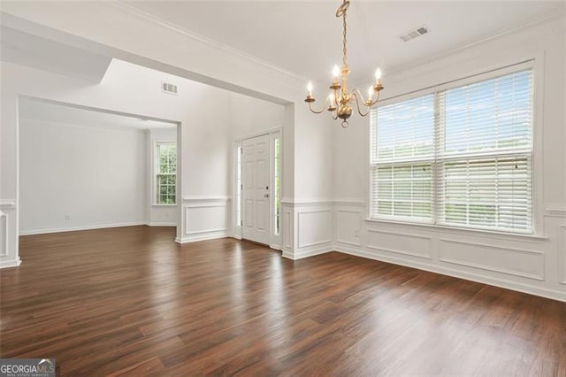 606 Hay Meadow Pl, Acworth, GA 30102 - empty room featuring a chandelier, dark wood-style flooring, wainscoting, ornamental molding, and a decorative wall
