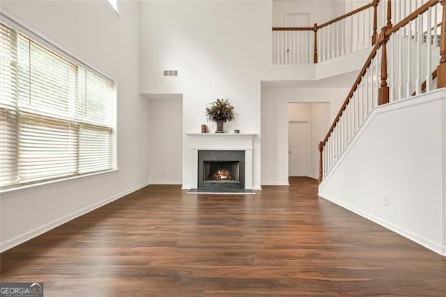 606 Hay Meadow Pl, Acworth, GA 30102 - unfurnished living room with a towering ceiling, stairs, wood finished floors, a fireplace with flush hearth, and baseboards