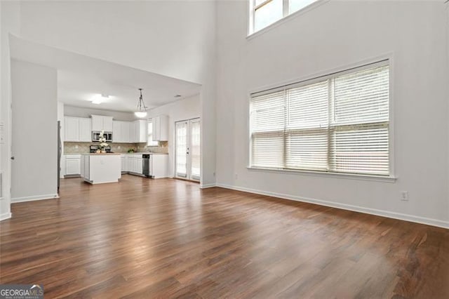 606 Hay Meadow Pl, Acworth, GA 30102 - unfurnished living room featuring dark wood-style flooring, baseboards, and a high ceiling