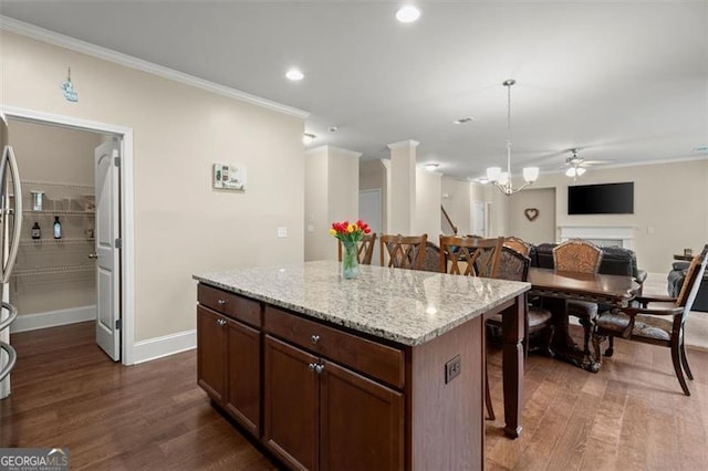 1709 Grove Ct, Conyers, GA 30013 - kitchen with ornamental molding, a breakfast bar, dark wood-style flooring, a ceiling fan, and a kitchen island
