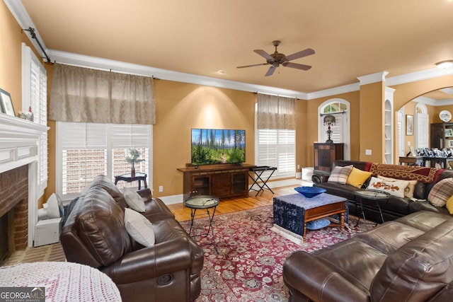 1014 Overlook Dr, Villa Rica, GA 30180 - living room featuring ornamental molding, a ceiling fan, arched walkways, a fireplace, and wood finished floors