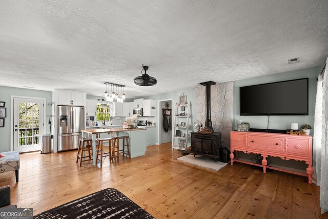 366 Crabapple Rdg, Clarkesville, GA 30523 - living room featuring a textured ceiling, light wood-style floors, a wood stove, and a chandelier