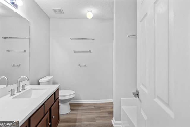 3315 Brookfield Dr, Austell, GA 30106 - full bathroom with toilet, vanity, wood finished floors, a textured ceiling, and a tub to relax in