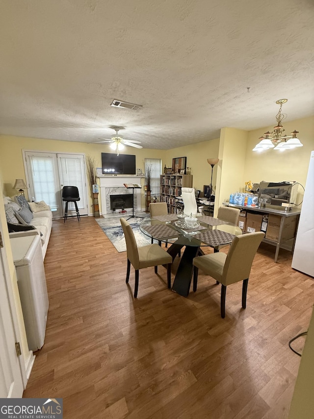 6550 Wellington Chase Ct, Lithonia, GA 30058 - dining area featuring wood finished floors, a fireplace, a textured ceiling, ceiling fan, and a chandelier