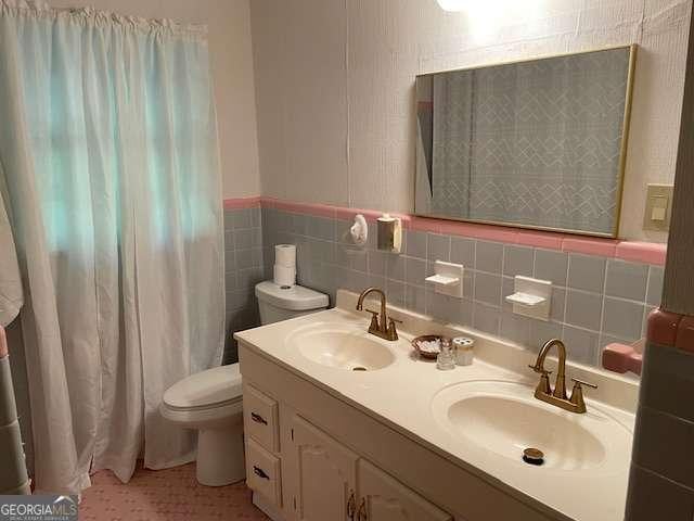 1470 Dunn Rd, Cumming, GA 30040 - full bath featuring double vanity, tile walls, a wainscoted wall, and a shower with shower curtain