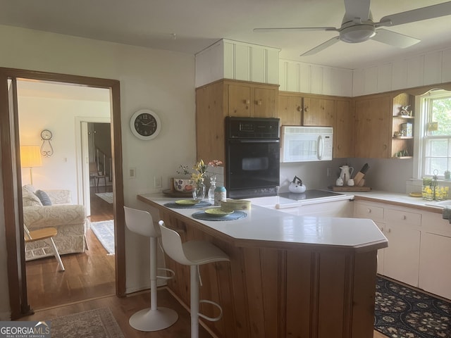 1470 Dunn Rd, Cumming, GA 30040 - kitchen with oven, white microwave, wood finished floors, light countertops, and ceiling fan