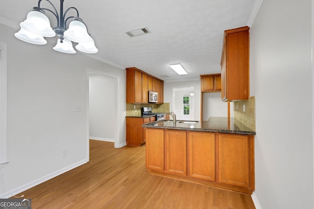4009 Riverstone Dr, Suwanee, GA 30024 - kitchen featuring stainless steel appliances, a chandelier, light wood-style floors, decorative backsplash, and ornamental molding