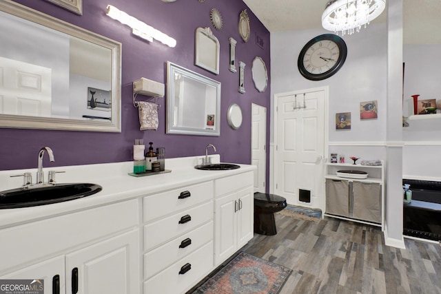 404 Carruth Rd, Winder, GA 30680 - bathroom featuring double vanity, wood finished floors, toilet, and a chandelier