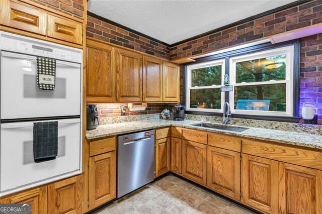 190 Roberts Way, Cornelia, GA 30531 - kitchen featuring stainless steel dishwasher, white double oven, brick wall, a sink, and brown cabinetry