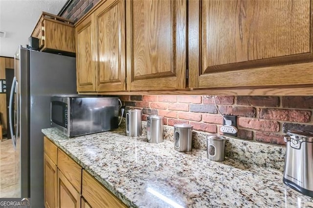 190 Roberts Way, Cornelia, GA 30531 - kitchen featuring tasteful backsplash, light stone countertops, brown cabinets, and freestanding refrigerator