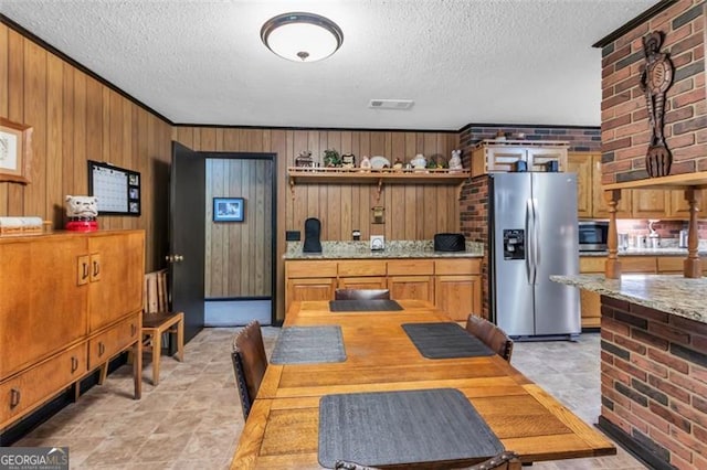 190 Roberts Way, Cornelia, GA 30531 - kitchen with stainless steel appliances, a textured ceiling, brick wall, wood walls, and brown cabinets
