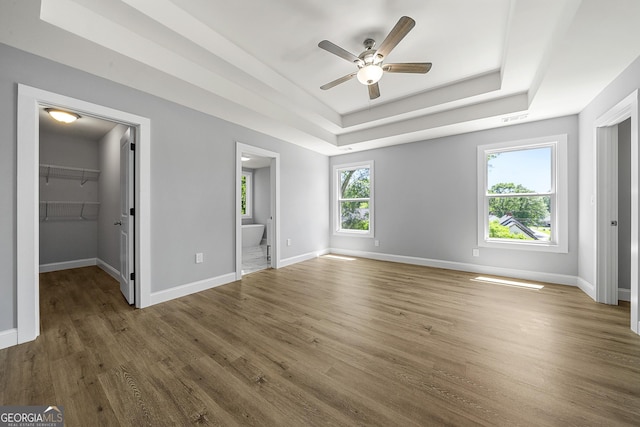 142 Arnco 3rd St, Newnan, GA 30263 - unfurnished bedroom featuring wood finished floors, a raised ceiling, a walk in closet, baseboards, and connected bathroom