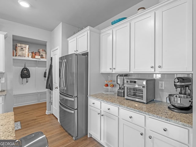 445 Sawmill Trce, Hampton, GA 30228 - kitchen with stainless steel refrigerator with ice dispenser, white cabinets, light wood-style floors, tasteful backsplash, and light stone counters