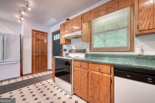 2309 Ridgecrest Cir, Hiawassee, GA 30546 - kitchen with white appliances, under cabinet range hood, light flooring, dark countertops, and brown cabinets
