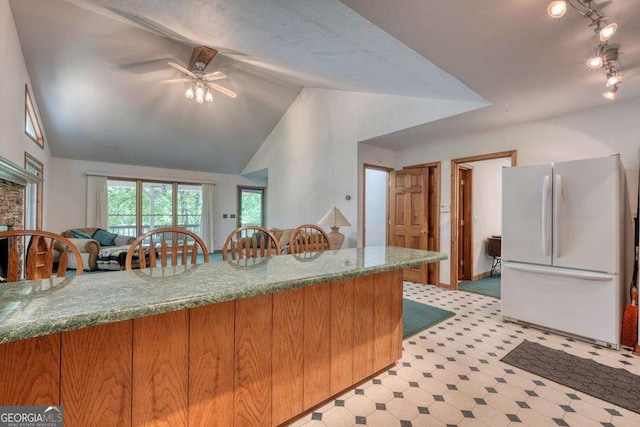 2309 Ridgecrest Cir, Hiawassee, GA 30546 - kitchen featuring freestanding refrigerator, stone counters, lofted ceiling, ceiling fan, and brown cabinetry