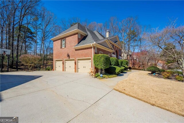 3410 Kates Way, Duluth, GA 30097 - view of property exterior featuring an attached garage, driveway, brick siding, and a chimney