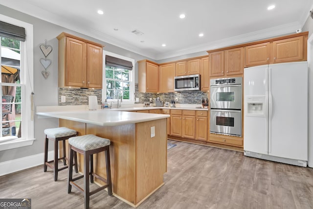 285 Finsbury Park Ct, Suwanee, GA 30024 - kitchen featuring stainless steel appliances, ornamental molding, decorative backsplash, a peninsula, and a breakfast bar