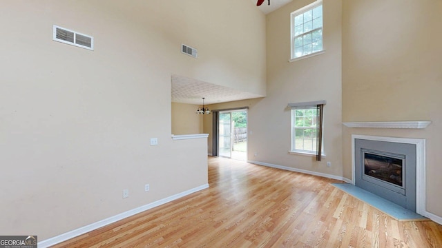 176 Silver Fox Trl, Dallas, GA 30157 - unfurnished living room featuring light wood-type flooring, healthy amount of natural light, baseboards, a fireplace with flush hearth, and a high ceiling