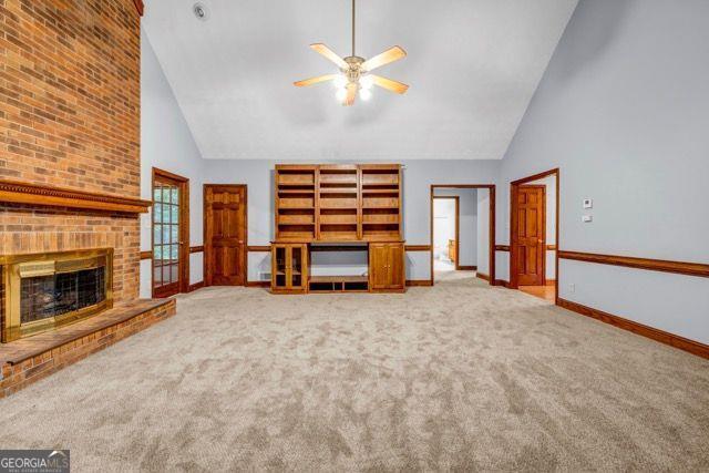 362 Clyde Ct, Mcdonough, GA 30252 - unfurnished living room with high vaulted ceiling, a ceiling fan, carpet floors, baseboards, and a brick fireplace
